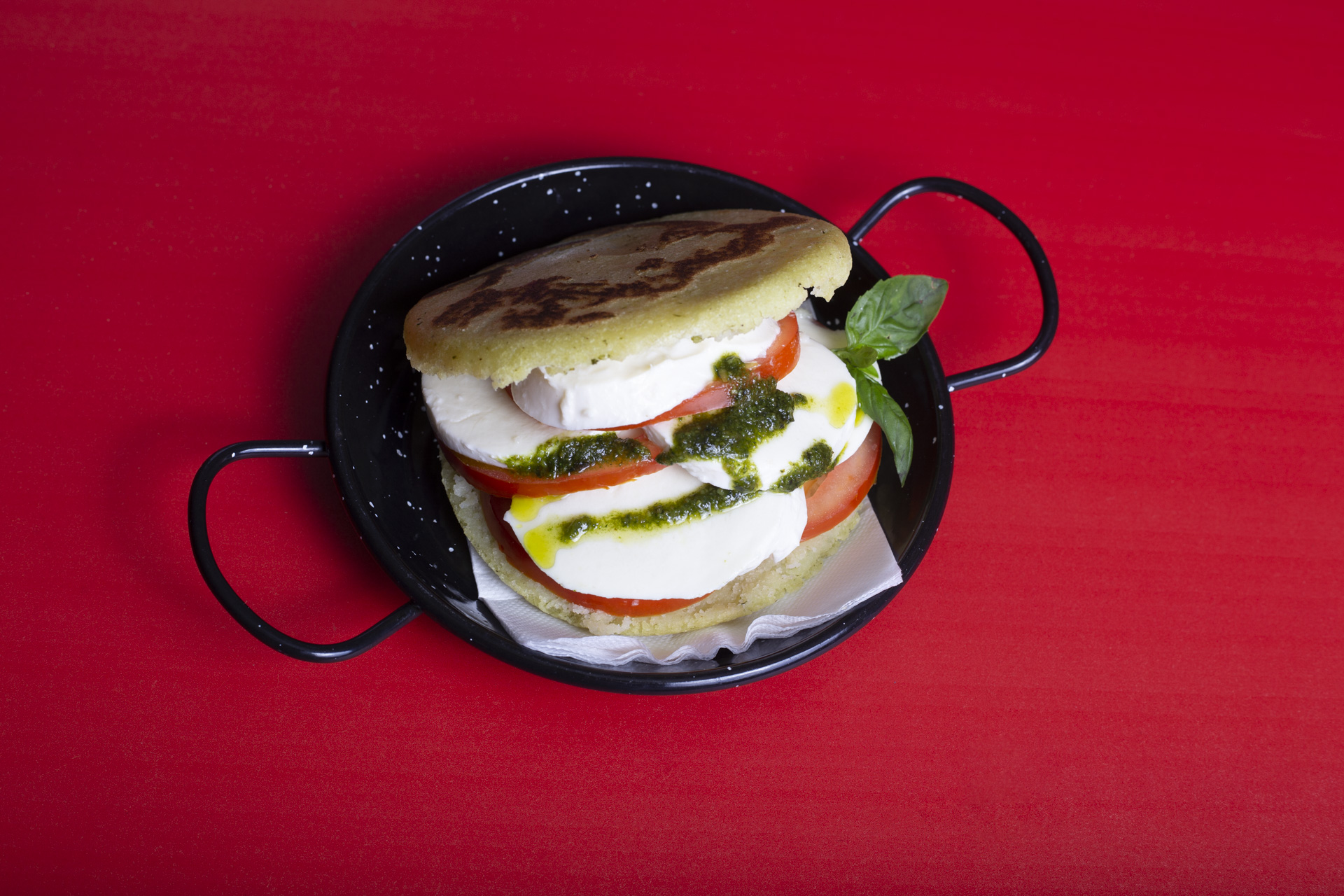 Arepa servida en una cazuela sobre fondo rojo